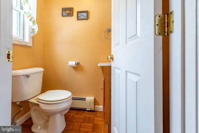 bathroom featuring toilet, a baseboard radiator, and parquet floors