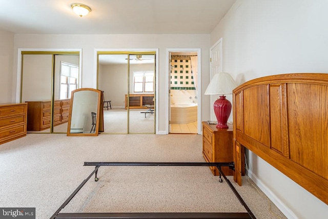 carpeted bedroom with multiple closets and ensuite bathroom