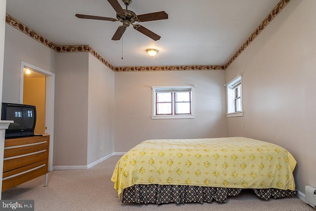 carpeted bedroom with ceiling fan and a baseboard radiator