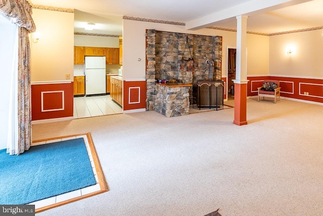 living room with light carpet, a wood stove, beam ceiling, and decorative columns