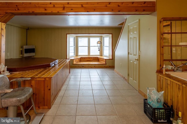 kitchen featuring heating unit, light tile patterned floors, and wooden walls