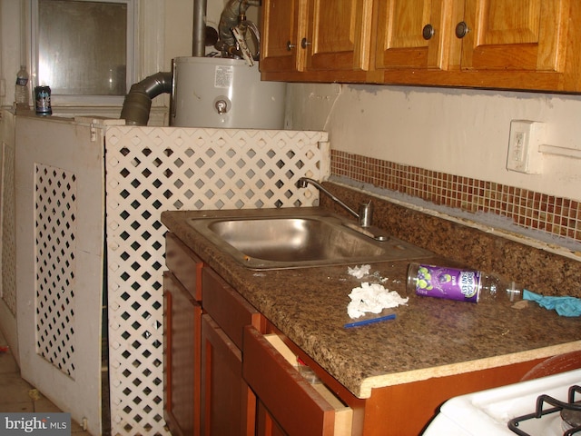 kitchen featuring dark stone countertops, water heater, backsplash, and sink