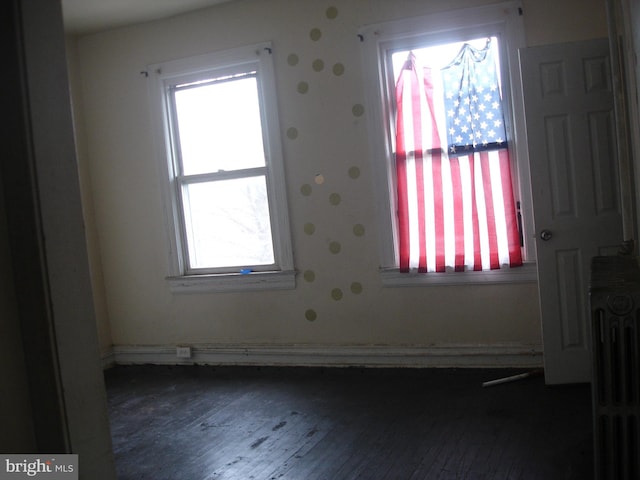 spare room with dark hardwood / wood-style flooring, plenty of natural light, and radiator