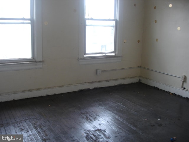 spare room with dark hardwood / wood-style flooring and plenty of natural light