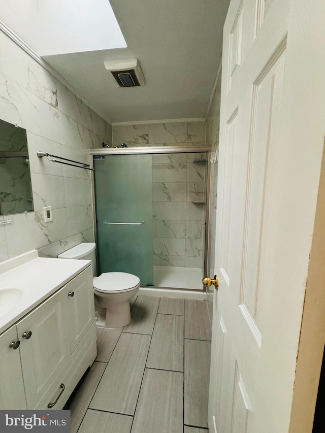 bathroom with toilet, tile floors, a shower with shower door, and vanity