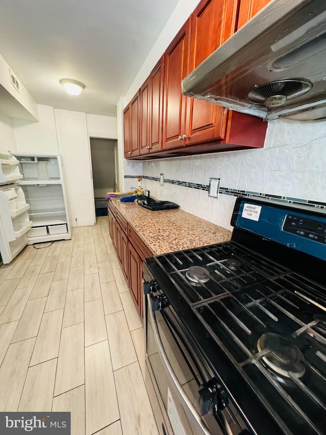 kitchen with stainless steel range oven, backsplash, and light stone counters