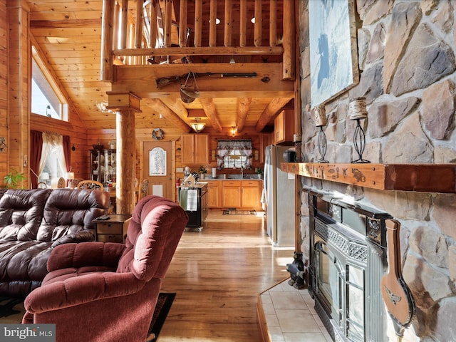 living room with wooden ceiling, a stone fireplace, light hardwood / wood-style flooring, lofted ceiling with beams, and wooden walls