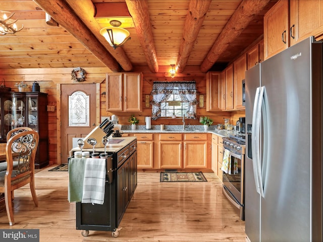 kitchen with light wood-type flooring, stainless steel appliances, wooden walls, sink, and beam ceiling