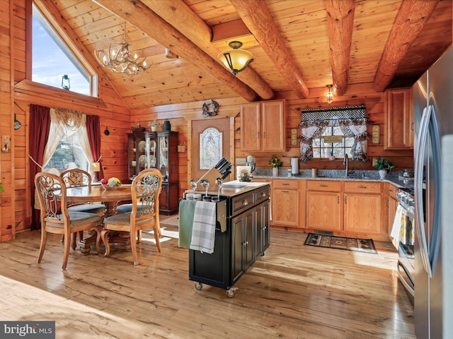 kitchen with pendant lighting, light hardwood / wood-style floors, a notable chandelier, and wood walls