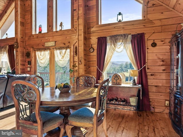 dining room featuring wood walls, high vaulted ceiling, wood ceiling, and hardwood / wood-style flooring