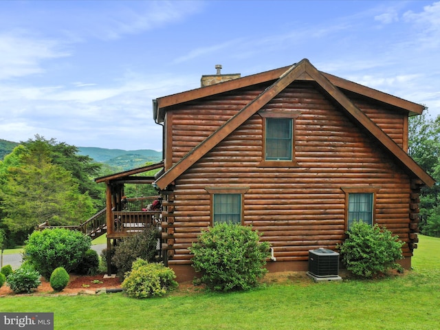 view of property exterior featuring a mountain view, a yard, and central AC