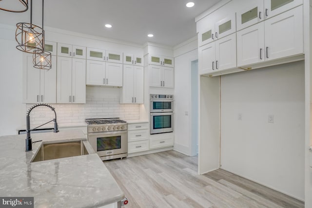 kitchen with white cabinetry, sink, appliances with stainless steel finishes, light stone countertops, and hanging light fixtures