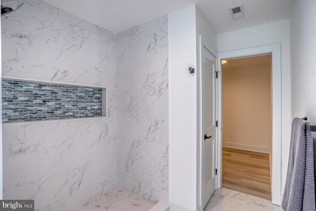 bathroom with hardwood / wood-style flooring and a tile shower