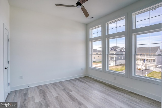 empty room with ceiling fan and light hardwood / wood-style flooring