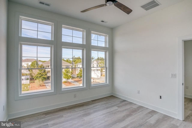 spare room featuring light wood-type flooring, plenty of natural light, and ceiling fan