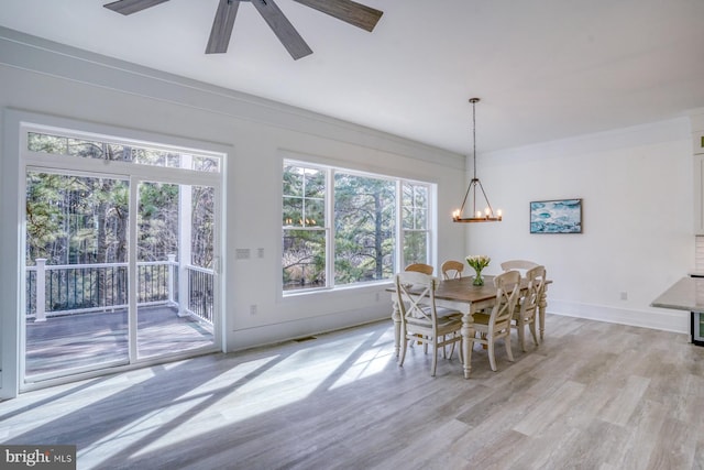 dining area with light wood-type flooring and ceiling fan with notable chandelier