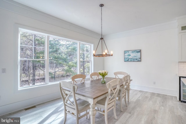 dining space with light hardwood / wood-style floors, a healthy amount of sunlight, and crown molding