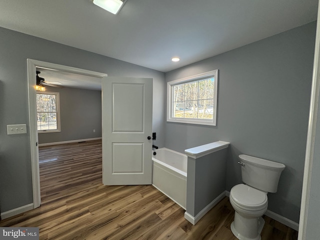 bathroom with a washtub, wood-type flooring, and toilet