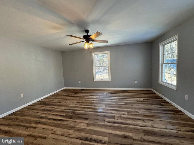 spare room with ceiling fan, a wealth of natural light, and dark hardwood / wood-style flooring