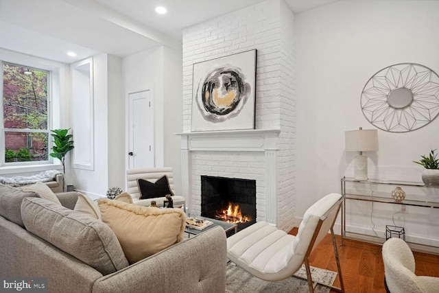 sitting room with brick wall, a fireplace, and wood-type flooring