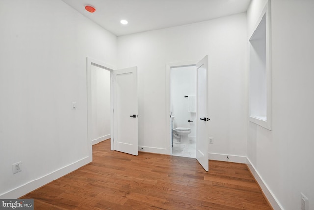 unfurnished bedroom with connected bathroom and light hardwood / wood-style floors