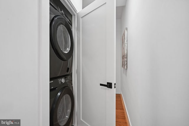 laundry room with hardwood / wood-style floors and stacked washing maching and dryer