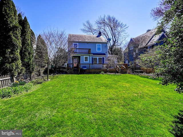 back of house with a deck and a lawn