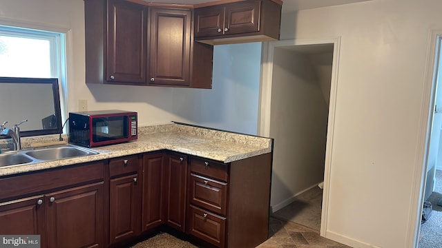 kitchen with dark tile flooring, dark brown cabinetry, and sink