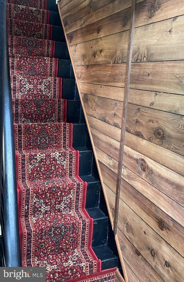 stairway featuring wooden walls