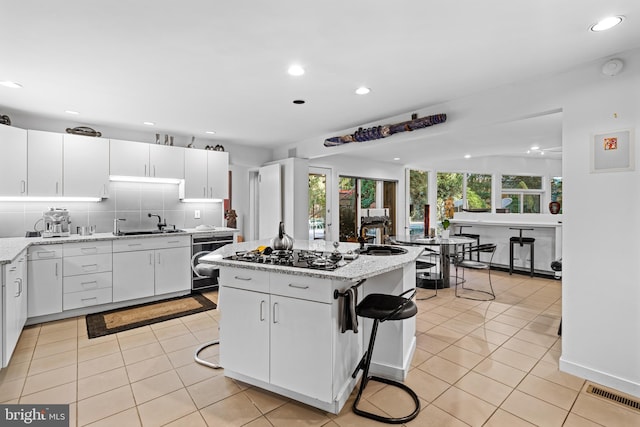 kitchen featuring white cabinets, a kitchen island, and light stone countertops