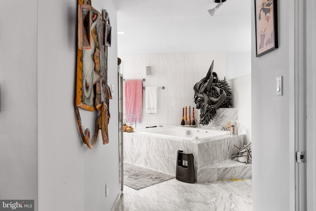 bathroom with tile flooring, tiled tub, and tile walls