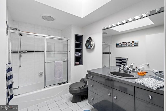 full bathroom with large vanity, toilet, combined bath / shower with glass door, tile flooring, and a skylight