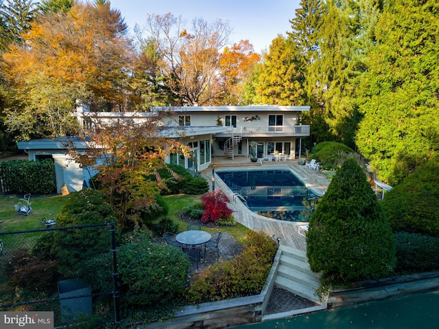 rear view of property featuring a patio and a fenced in pool