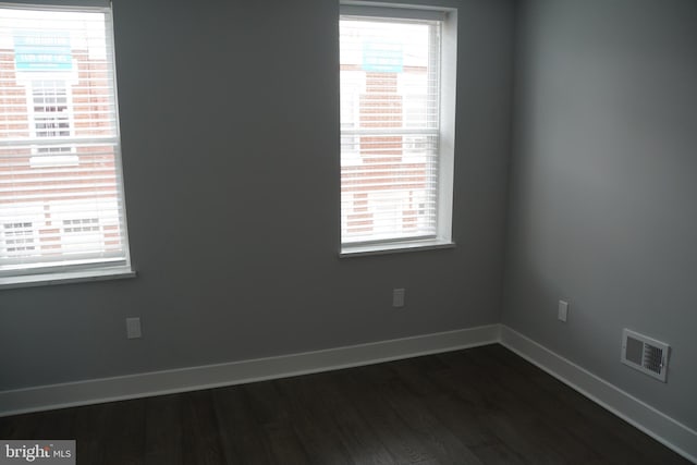 empty room with a healthy amount of sunlight and dark hardwood / wood-style floors