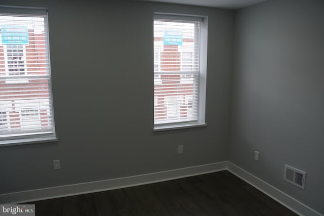 unfurnished room featuring a healthy amount of sunlight and dark hardwood / wood-style floors