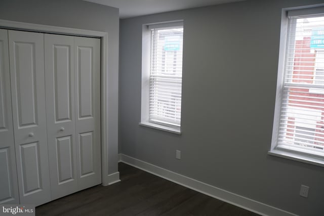 unfurnished bedroom with dark hardwood / wood-style floors and a closet