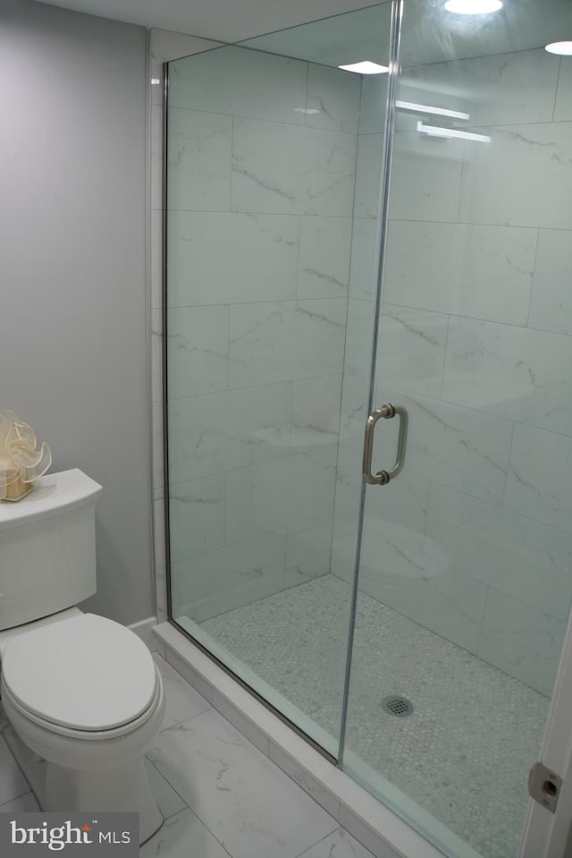 bathroom featuring tile flooring, a shower with door, and toilet