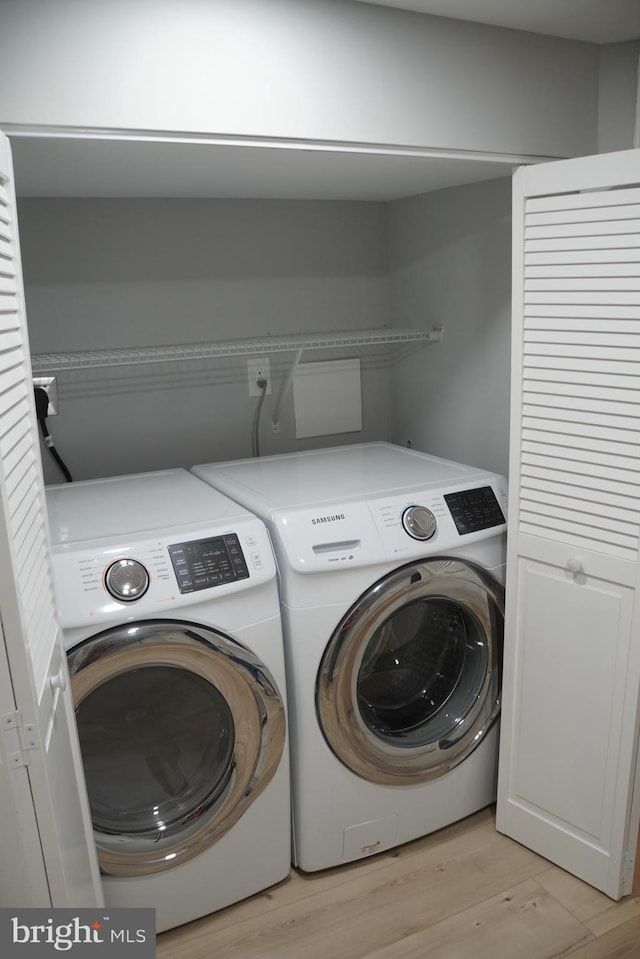 laundry area with hookup for an electric dryer, light hardwood / wood-style floors, and independent washer and dryer