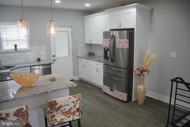 kitchen with white cabinets, backsplash, light stone countertops, and appliances with stainless steel finishes