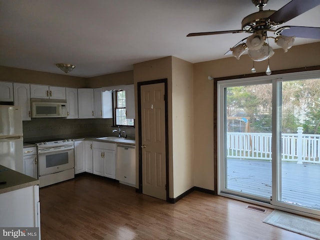 kitchen featuring white cabinets, sink, white appliances, and dark wood-type flooring