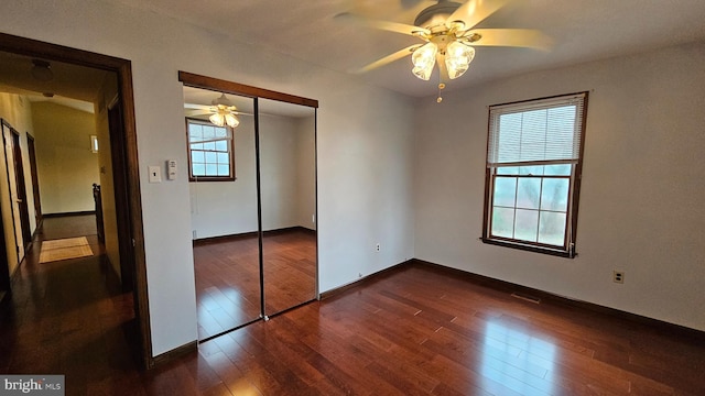 unfurnished bedroom featuring a closet, multiple windows, and dark hardwood / wood-style floors