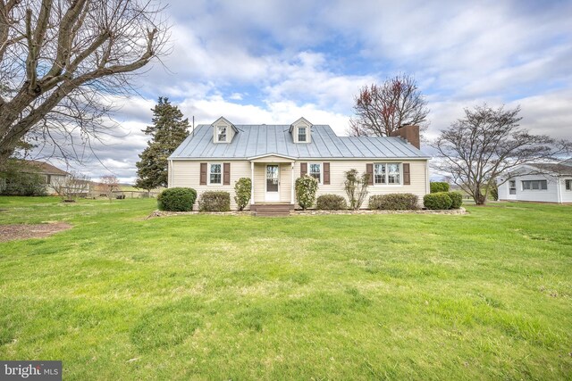 view of front of property with a standing seam roof, a front yard, a chimney, and metal roof
