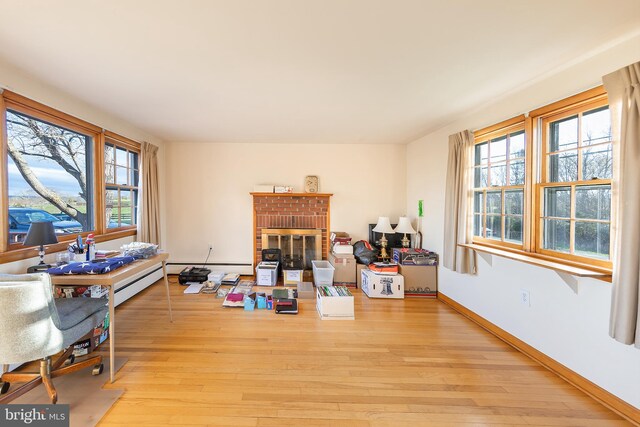 interior space featuring a brick fireplace, plenty of natural light, and light wood-style flooring