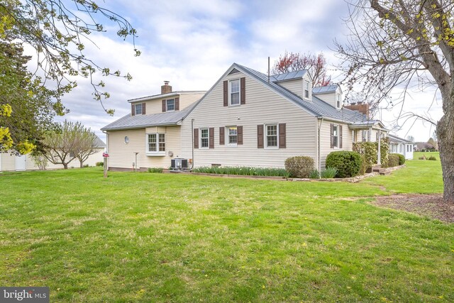 back of house with a lawn, a chimney, cooling unit, and metal roof