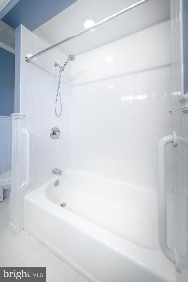 full bathroom featuring toilet, tile patterned floors, wainscoting, and shower / bathing tub combination