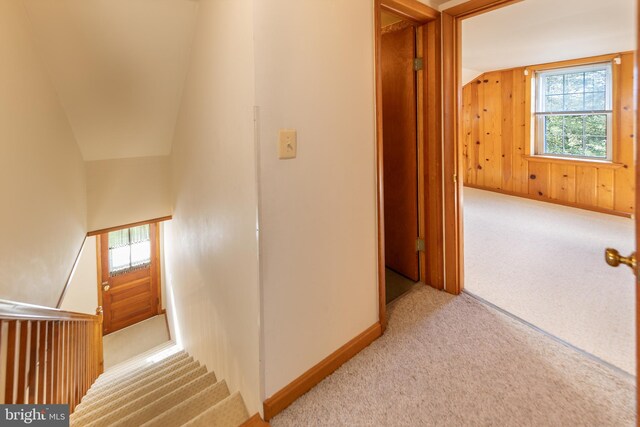 hall featuring baseboards, vaulted ceiling, and carpet