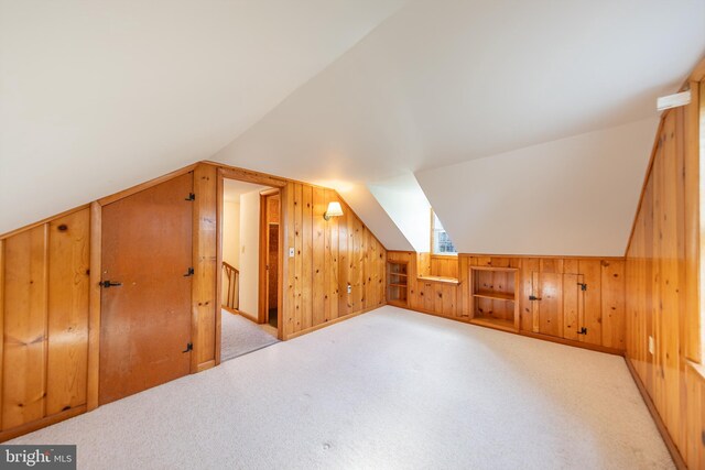bonus room with wooden walls, carpet, and lofted ceiling