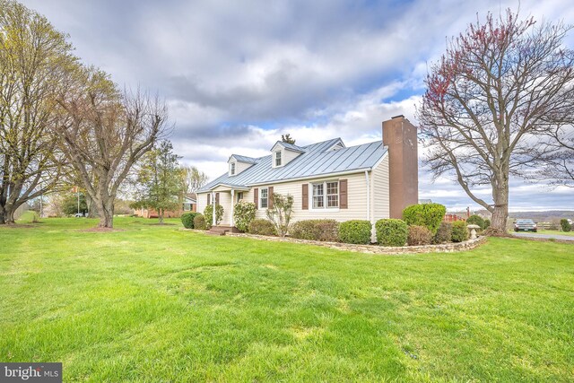 view of front facade with a front lawn, metal roof, a chimney, and a standing seam roof