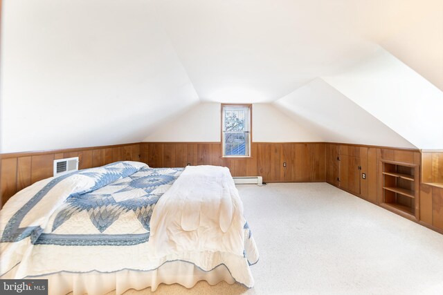 bedroom featuring visible vents, vaulted ceiling, wainscoting, a baseboard radiator, and wooden walls