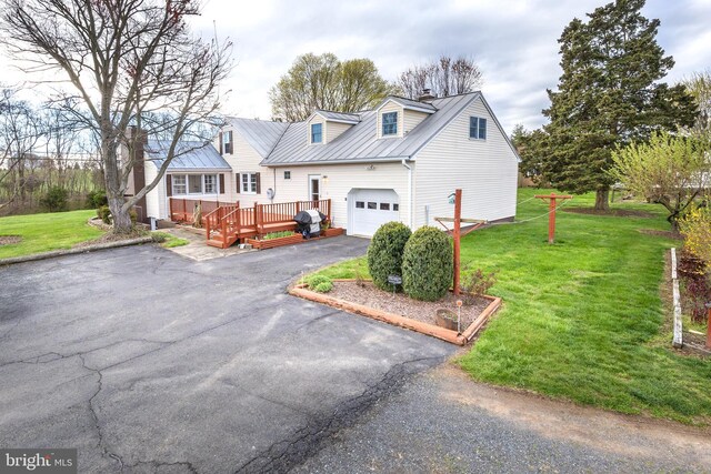 view of front of property with a wooden deck, driveway, a front yard, and metal roof